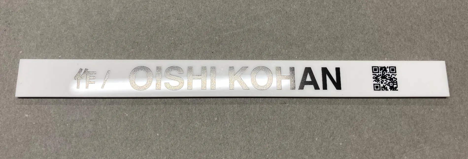 プラスチックに文字やQRを印刷してキャプションの作成して光が反射している様子